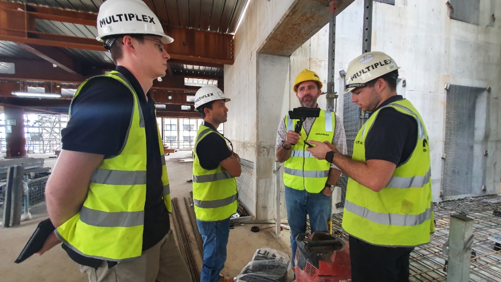 Site managers on an inspection round, one checking a mobile phone while a colleague films with a stabilised GoPro.