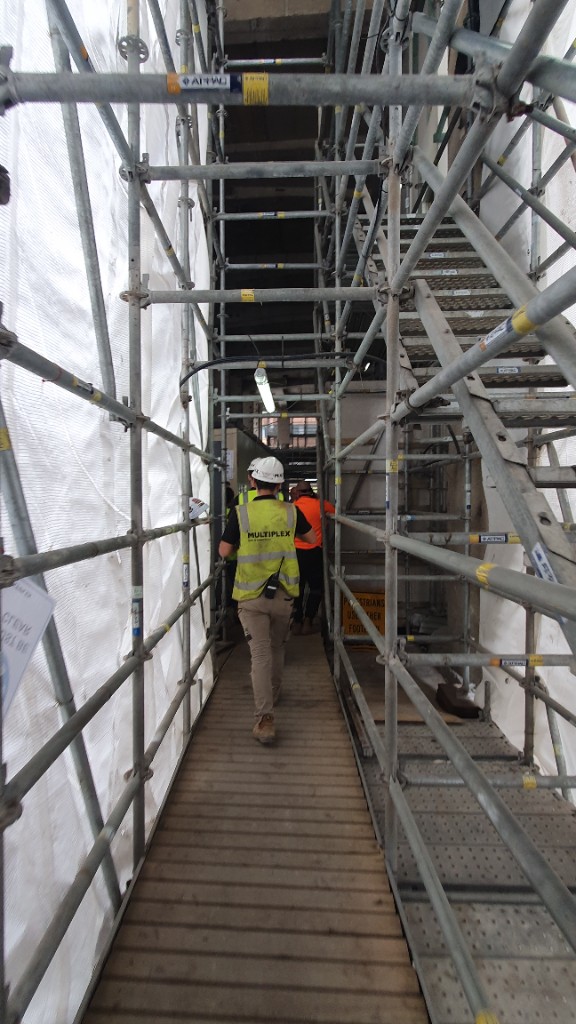 Site supervisor walking through scaffold walkway.